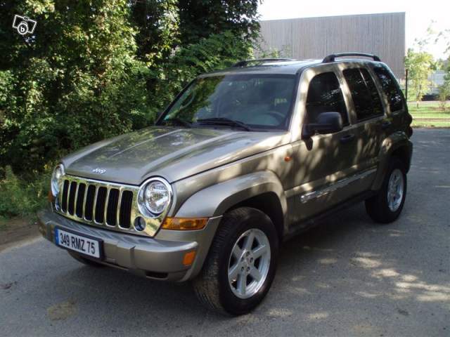 Gold Jeep Grand Cherokee with a chrome grille and roof rack, parked on asphalt