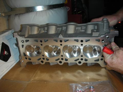 1992 Ford Crown Victoria - A person is holding a newly machined engine cylinder head, ready for installation.