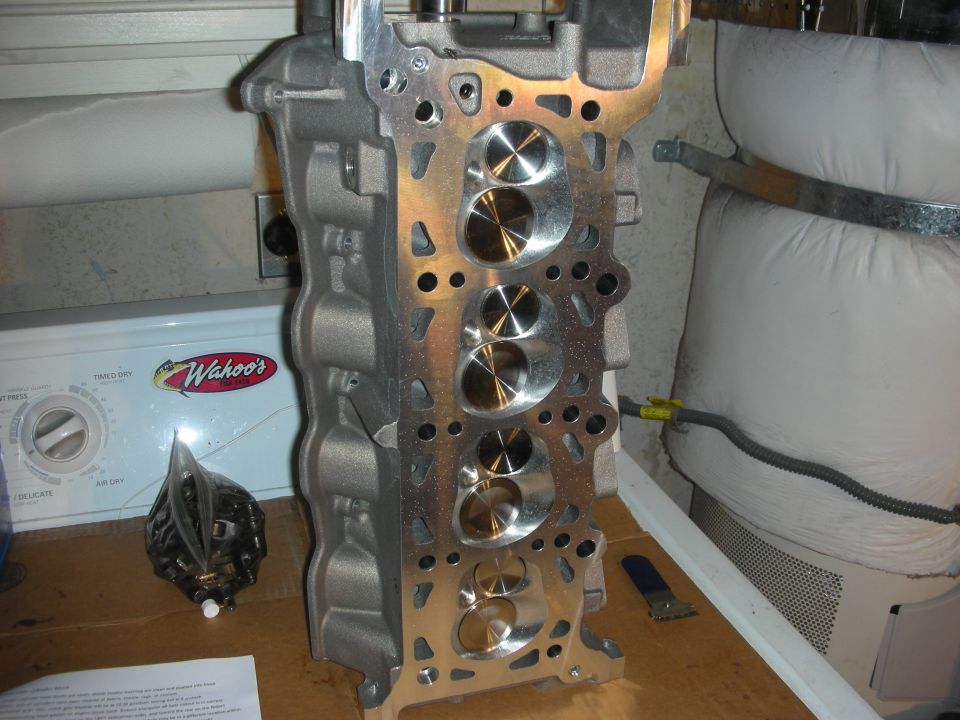 Engine cylinder head with polished intake valves, resting on a table next to a Wahoo's dryer