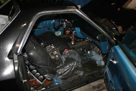 1973 Ford Ranchero - The interior of a car is shown, with seats covered and the dashboard exposed, next to another vehicle.