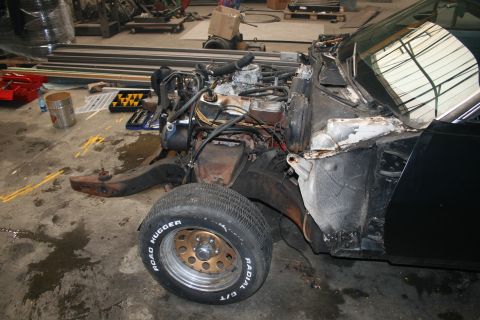 1973 Ford Ranchero - The front end of a black vehicle, possibly undergoing repairs, is visible with its engine compartment exposed.