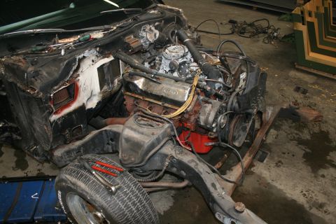 1973 Ford Ranchero - Vehicle engine and chassis undergoing disassembly, with tools visible on a tire.