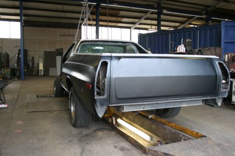1973 Ford Ranchero - This vehicle is in a workshop, suspended by chains, undergoing repairs or restoration.