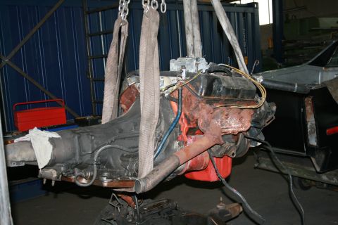 1973 Ford Ranchero - An engine and transmission are suspended by chains, likely during a repair or removal process in a workshop.