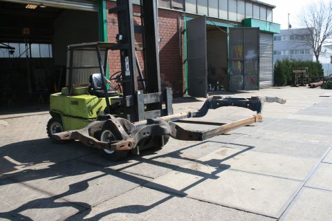 1973 Ford Ranchero - A vehicle frame is being moved by a forklift in an industrial area.