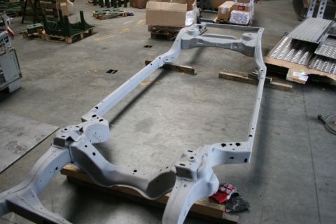 1973 Ford Ranchero - A bare vehicle frame sits on wooden blocks, likely awaiting restoration or assembly in a workshop environment.