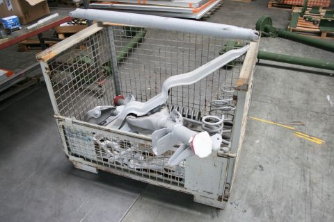 1973 Ford Ranchero - Automotive suspension parts are stored in a wire cage in a warehouse setting.
