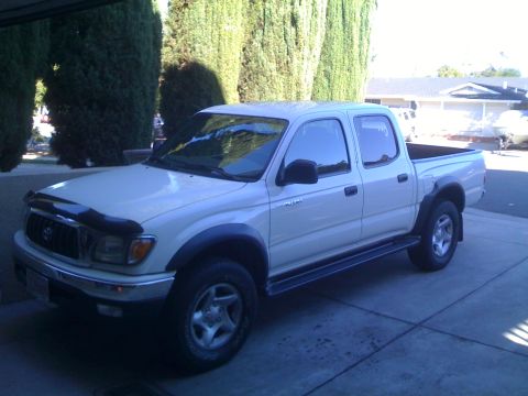 1986 Ford Bronco - This white Toyota Tacoma pickup truck is parked on a concrete driveway.