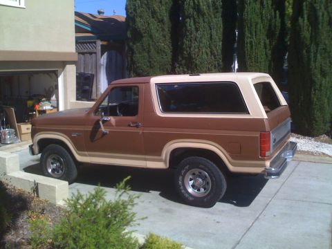 1986 Ford Bronco - This two-tone Ford Bronco is parked in front of a house with a garage.