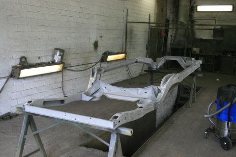1973 Ford Ranchero - A bare vehicle frame is supported by sawhorses in a workshop setting, awaiting restoration.