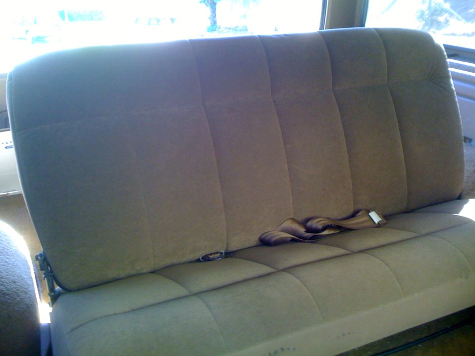 Tan cloth rear bench seat with seatbelts, viewed from the side