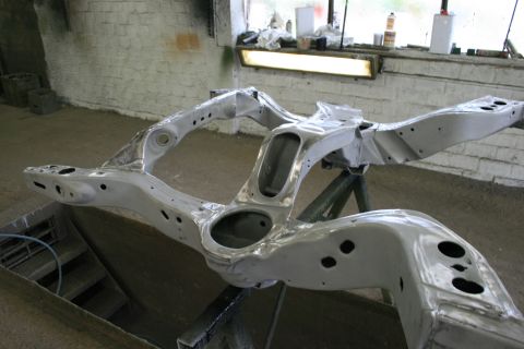 1973 Ford Ranchero - Bare metal car frame assembly on a stand in a workshop.