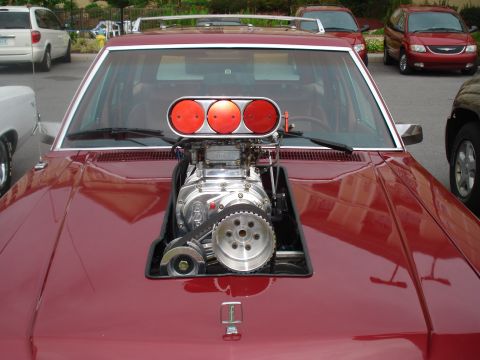 1994 Ford F-350 - Customized car with a prominent supercharger installation on the hood, parked outdoors with other vehicles nearby.