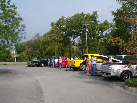 1994 Ford F-350 - Several pickup trucks are parked in a line, with people gathered around them.