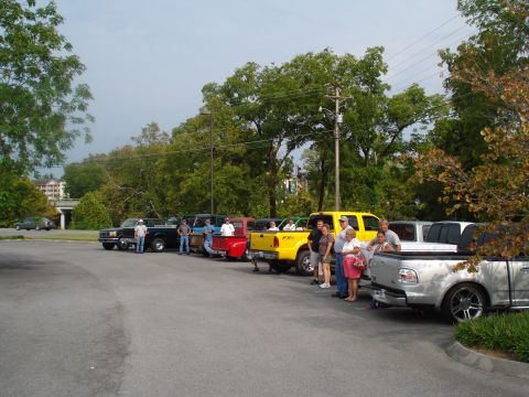 1994 Ford F-350 - A group of people gathered around a line of pickup trucks parked in an outdoor lot.