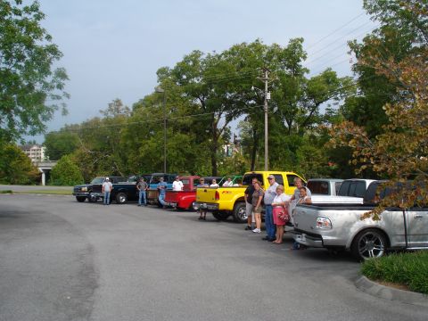 1994 Ford F-350 - A group of people gather around a line of pickup trucks parked in an outdoor lot.