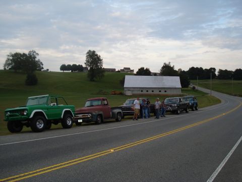 1994 Ford F-350 - Several classic Ford trucks and SUVs are lined up on the side of a rural road.