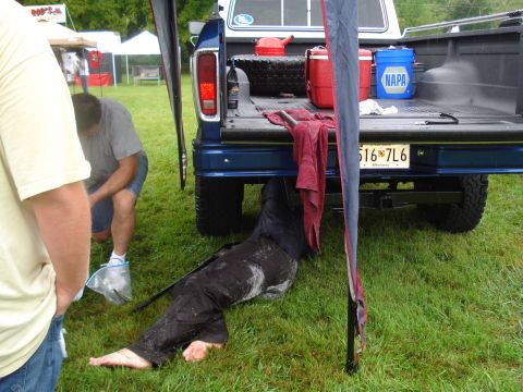 1994 Ford F-350 - A person is working on the underside of a blue pickup truck at an outdoor event.