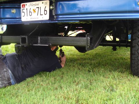 1994 Ford F-350 - A person works on the rear hitch of a blue truck, with a Maryland license plate in view.