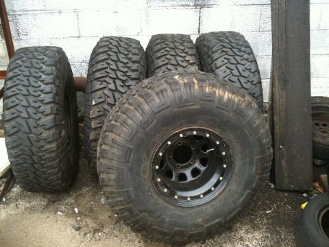 1995 Ford Bronco - Set of four aggressive off-road tires, one mounted on a black beadlock wheel.