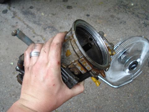 1994 Ford F-350 - A carburetor is held in a hand, with a fan visible behind it.