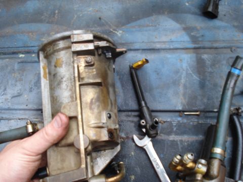 1994 Ford F-350 - A hand holds a used fuel filter housing, with a wrench and hoses visible in the background.
