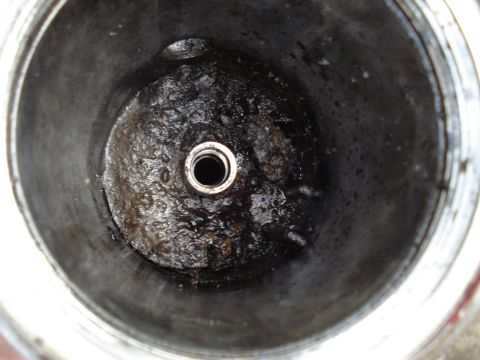 1994 Ford F-350 - Close-up view of a dirty engine component, showing significant oil buildup and a central threaded hole.