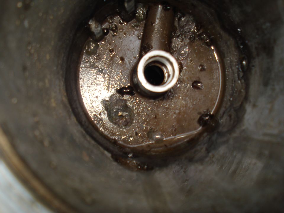 Close-up of a dirty engine oil filter housing with a metal fitting