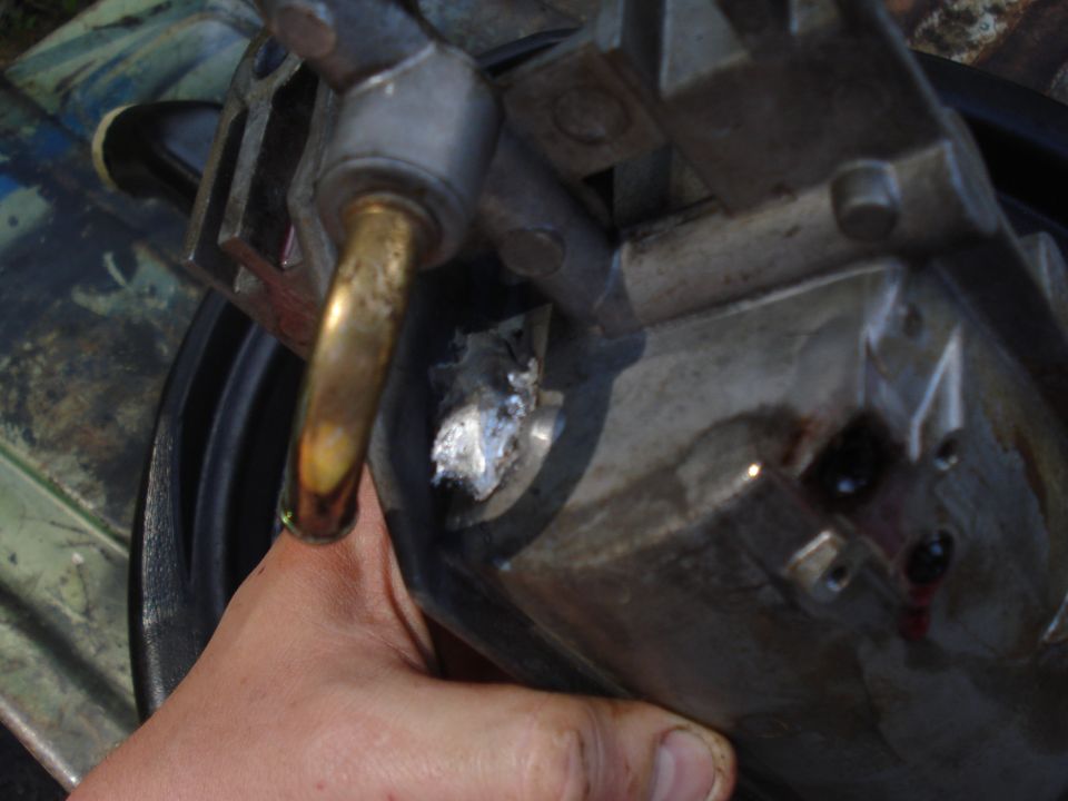 Engine part with brass fitting, showing aluminum repair and red fluid residue