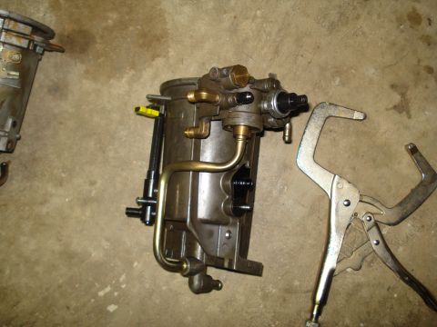 1994 Ford F-350 - A disassembled fuel filter housing sits on a concrete floor next to a locking clamp.