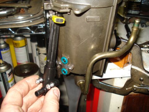 1994 Ford F-350 - A hand holds a black fuel line assembly connected to a larger engine component, with metal tubing and clamps visible.