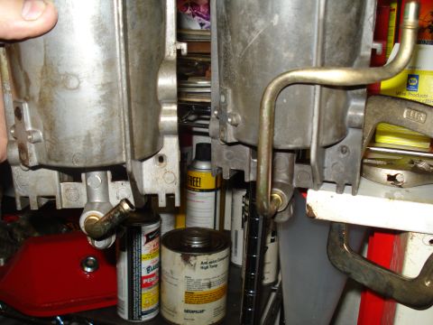 1994 Ford F-350 - Close-up view of two carburetors, likely for an engine, with visible fuel lines and surrounding workshop items.