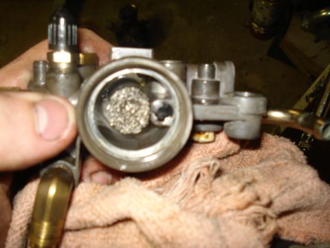 1994 Ford F-350 - Close-up view of a carburetor, showing a fuel filter inside. The part is held over a cloth.