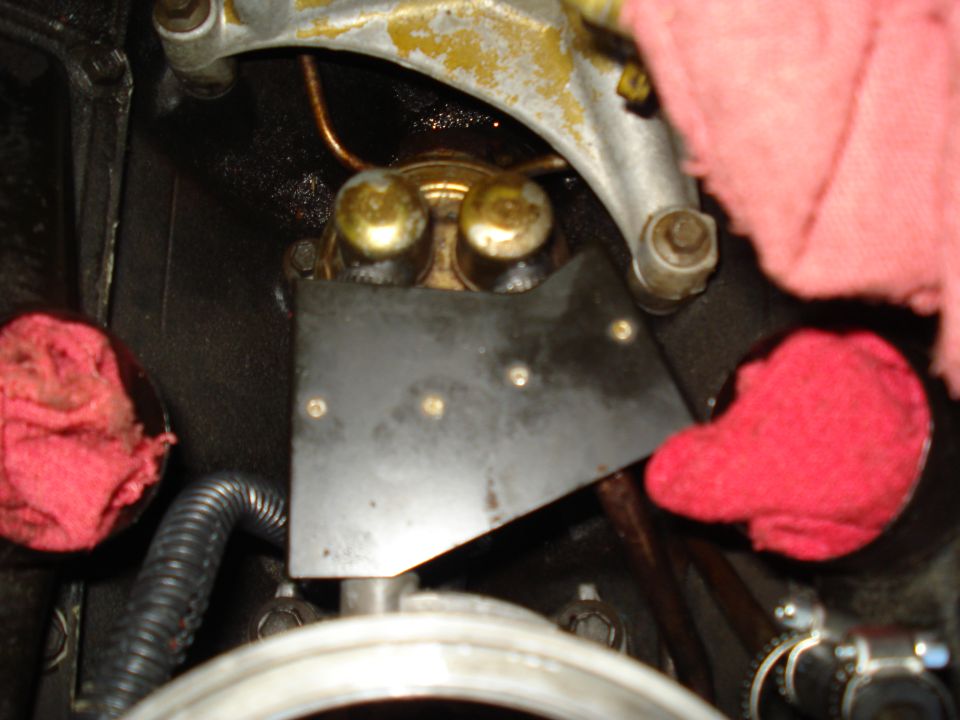Close-up of engine parts, possibly a fuel pump, with red rags stuffed around it