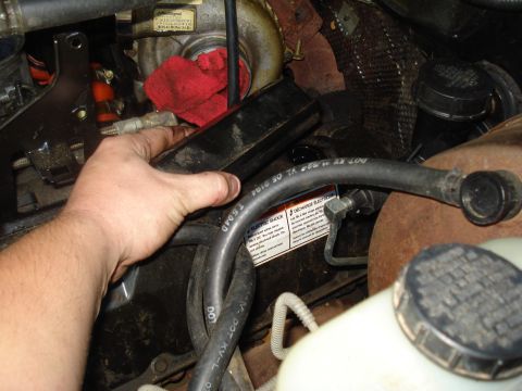 1994 Ford F-350 - Close-up view of a vehicle's engine bay, showing hoses and a turbocharger with a hand reaching in.