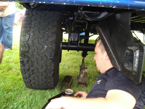1994 Ford F-350 - A man works on the undercarriage of a blue truck, focusing on the suspension and rear tire.