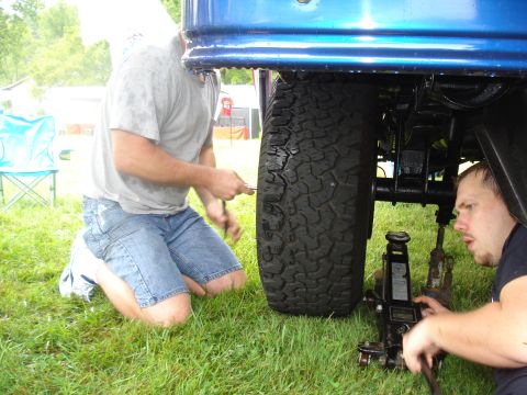1994 Ford F-350 - Two men are seen working on a truck's tire, with one operating a jack to lift the vehicle.