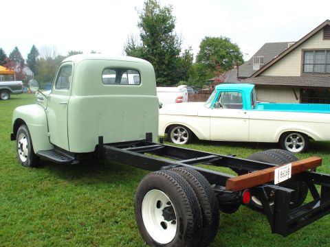1994 Ford F-350 - A light green truck chassis and cab is shown from the rear, with a white and blue truck behind it.