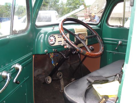 1994 Ford F-350 - The dashboard and steering wheel of a vintage green truck, showing its interior details and a radio microphone on the seat.