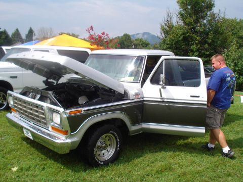 1994 Ford F-350 - A man stands by a vintage Ford F-Series truck with its hood open at an outdoor event.