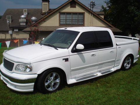 1994 Ford F-350 - This pickup truck has a custom body kit and chrome wheels, and is parked on a grassy lawn in front of a house.