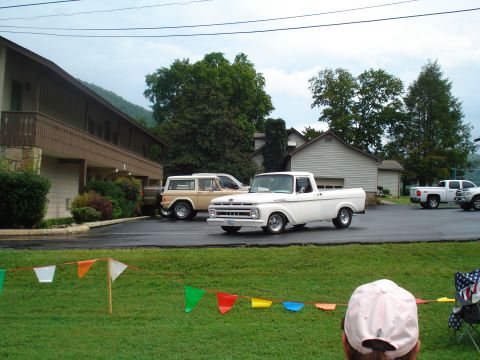 1994 Ford F-350 - A white pickup truck and a tan SUV are parked in a lot near a building.