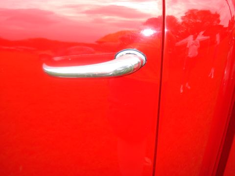 1994 Ford F-350 - A chrome door handle is visible on the bright red side of a truck. The Supermotors logo is in the corner.