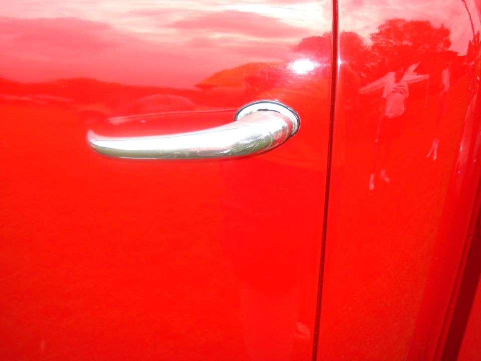 Close-up of a red truck's side door handle