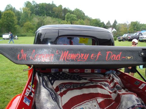 1994 Ford F-350 - A black pickup truck bed displays a memorial message on its tailgate and an American flag blanket.