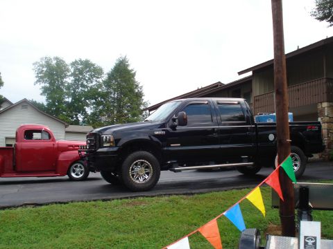 1994 Ford F-350 - A modern black Ford pickup truck is parked next to a vintage red pickup truck.
