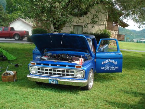 1994 Ford F-350 - A blue Ford pickup truck is parked on grass with its hood and door open, displaying custom text on the door.