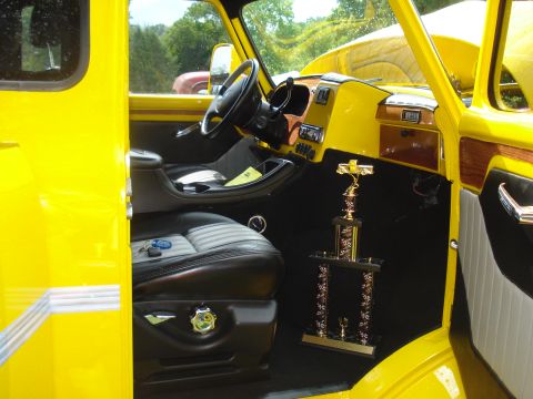 1994 Ford F-350 - The interior of a yellow truck shows custom seats, wood accents, and a large trophy.