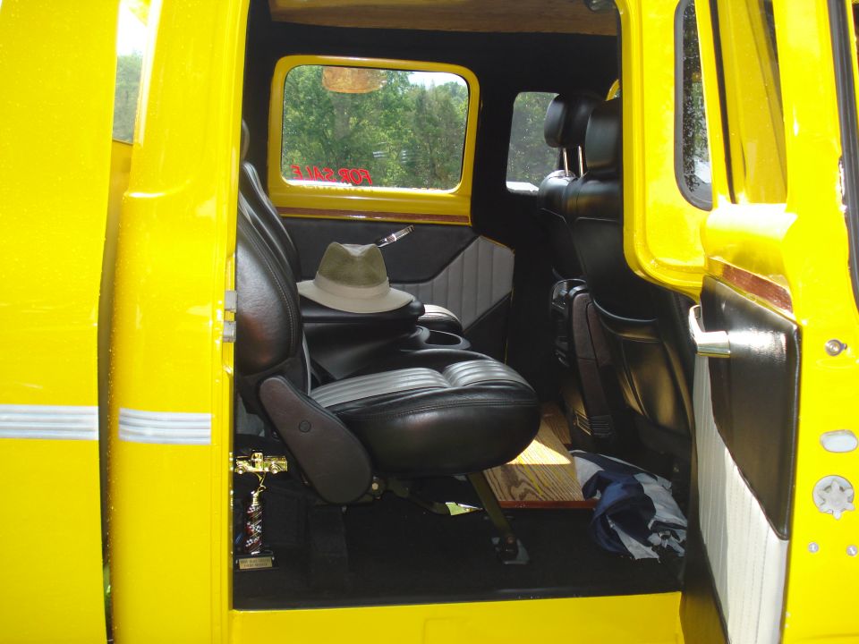 Yellow truck interior with black leather seats, a hat on the passenger seat, and a trophy on the floor