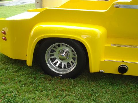 1994 Ford F-350 - Close-up of a custom yellow pickup truck bed, showing the rear wheel and exhaust pipe.